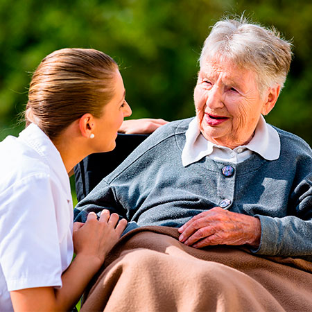 Group of seniors outdoors conversing with care provider